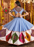 Woman wearing a colorful traditional outfit with a blue and patterned skirt in a decorated setting.