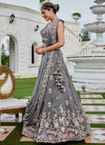 Woman in a gray embroidered saree standing outdoors with classical architecture in the background