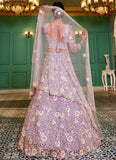 Woman in a floral embroidered lehenga with a matching dupatta in an elegant indoor setting.