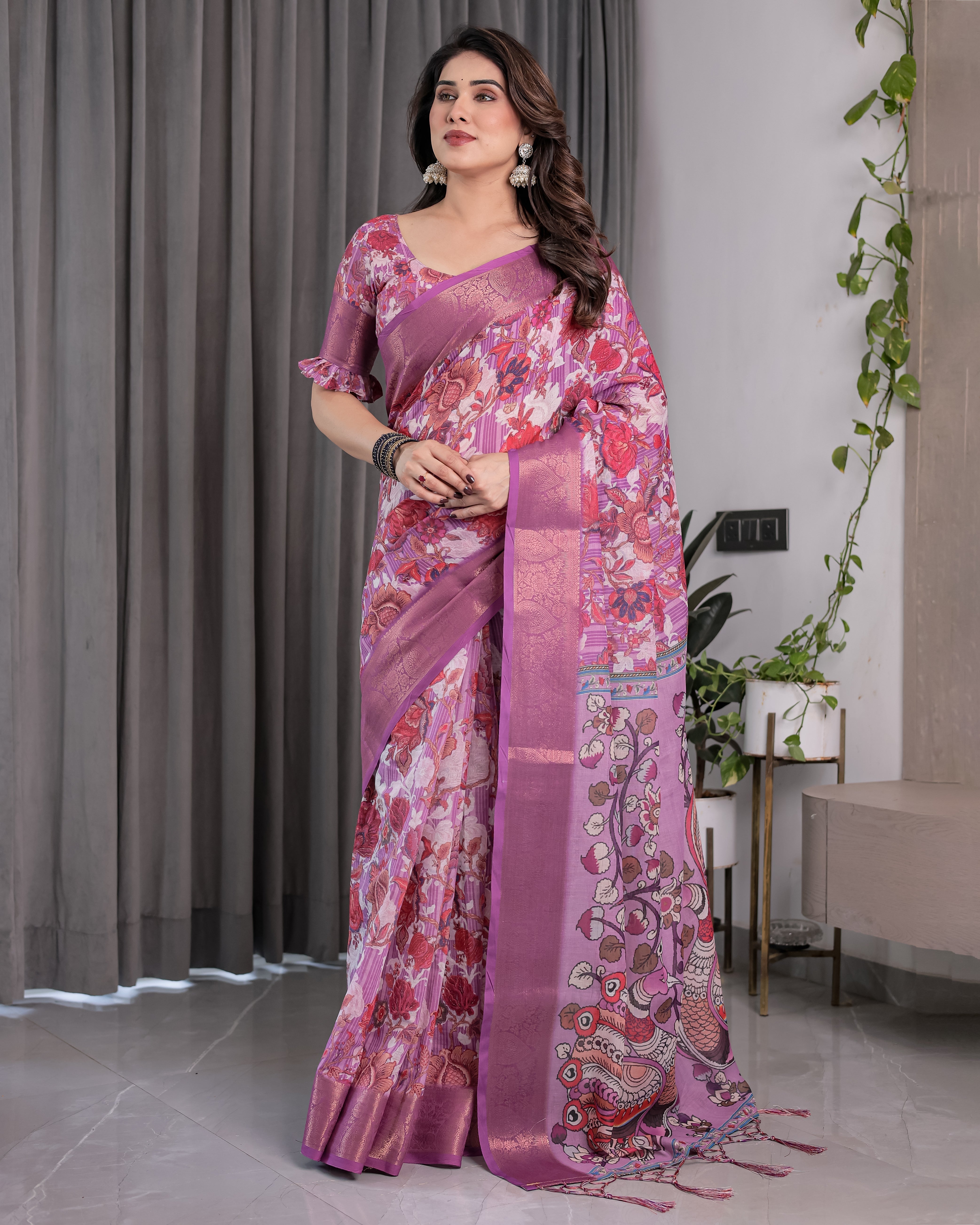 Woman wearing a pink saree with a floral pattern in an indoor setting.