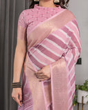 Woman wearing a pink saree with a striped pattern, standing against a neutral background.
