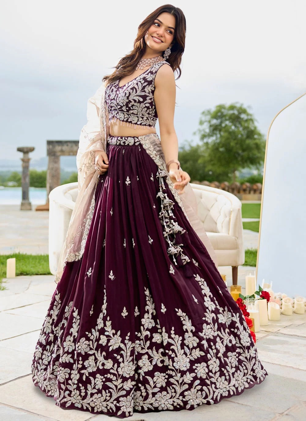 Woman in a purple and white embroidered traditional outfit standing outdoors.