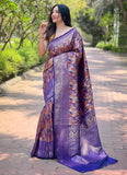 Woman wearing a purple saree with a pattern standing on a pathway in a garden.