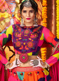 Woman in traditional colorful outfit with intricate patterns and jewelry against a vibrant background