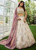 Woman in a floral lehenga with a purple dupatta standing outdoors.