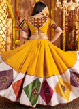 Woman in a traditional yellow and multicolored saree with a decorative backdrop