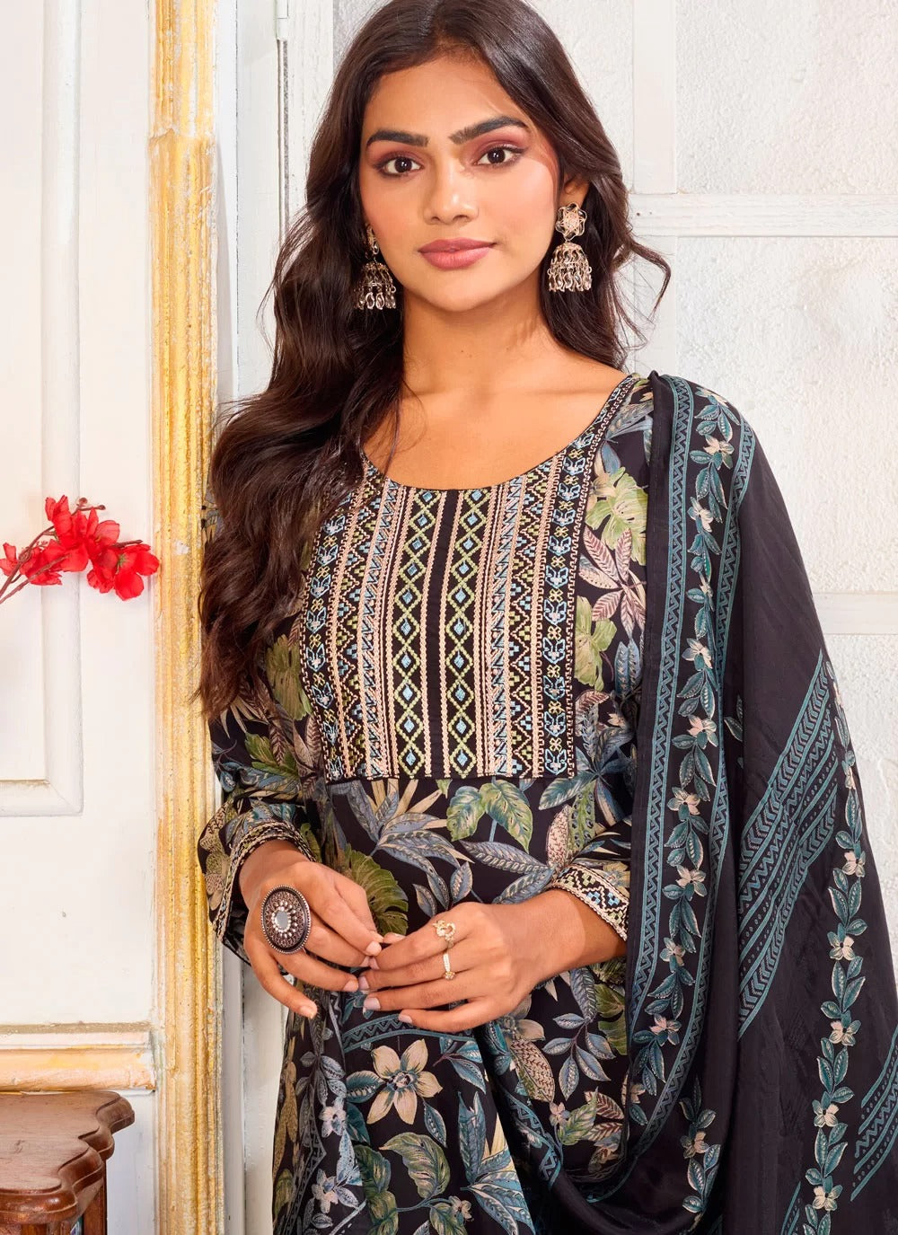 Woman wearing a traditional outfit with floral patterns indoors.