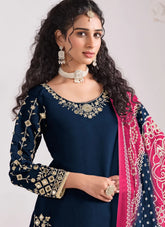 Woman wearing a navy blue embroidered outfit with a pink and white patterned dupatta.