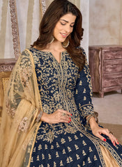 Woman wearing a navy blue embroidered traditional outfit with gold details indoors.