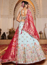 Woman in traditional outfit with red and light blue dress in a decorated room.