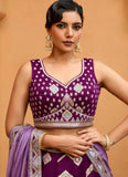 Woman wearing a purple traditional outfit with gold accents against a beige background