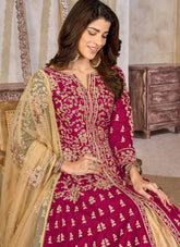 Woman wearing a traditional embroidered pink and gold outfit in an indoor setting.