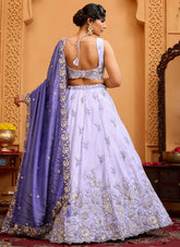 Woman in a white embroidered lehenga with a purple dupatta in an ornate setting