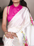 Woman wearing a white saree with floral patterns and a pink blouse.