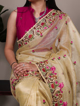 Woman wearing a beige saree with floral embroidery and a pink blouse.