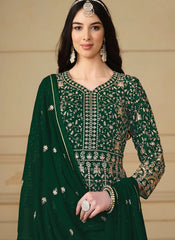 Woman wearing a green embroidered traditional outfit with a beige background