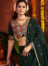 Woman in traditional dark green saree with colorful blouse against a decorative background