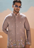 Man wearing a brown embroidered shirt with a desert landscape background