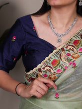 Woman wearing a navy blue blouse with floral embroidery and a silver necklace.