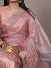 Woman wearing a pink saree with intricate designs against a neutral background