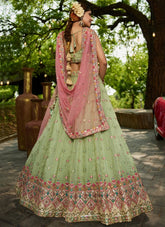 Woman in a traditional green and pink embroidered outfit standing outdoors.