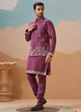 Man wearing a traditional purple outfit with floral patterns against a desert-themed background