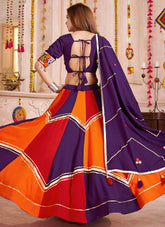 Woman wearing a colorful traditional outfit with a vibrant purple and orange design.