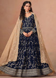 Woman wearing a navy blue embroidered dress with a beige dupatta against a beige background