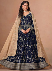 Woman wearing a navy blue embroidered dress with a beige dupatta against a beige background