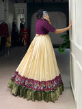 Woman taking a mirror selfie wearing a traditional outfit with a cream skirt and purple top.