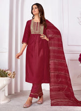 Woman wearing a maroon traditional outfit with a matching dupatta in a well-lit room.