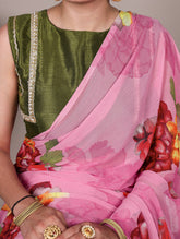 Person wearing a green blouse with a pink saree featuring floral patterns.