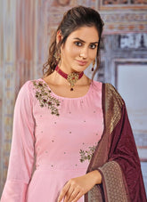 Woman wearing a pink traditional outfit with a maroon dupatta in an indoor setting