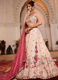Woman in a traditional embroidered outfit with a pink dupatta in an ornate setting