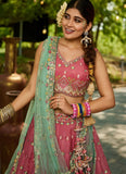 Woman in traditional pink and green embroidered outfit with jewelry outdoors