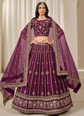 Woman wearing a traditional purple embroidered outfit with a matching dupatta.