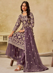 Woman wearing a purple traditional outfit with floral patterns in a neutral setting