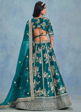 Teal embroidered traditional outfit with a sheer dupatta on a blue background