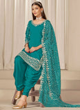 Woman wearing a teal traditional outfit with a matching dupatta against a neutral background