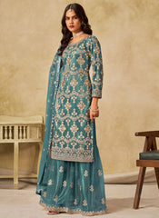 Woman wearing a teal embroidered traditional outfit against a beige background