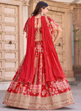 Woman wearing a traditional red and gold embroidered outfit with a matching dupatta against a rustic wooden door background.