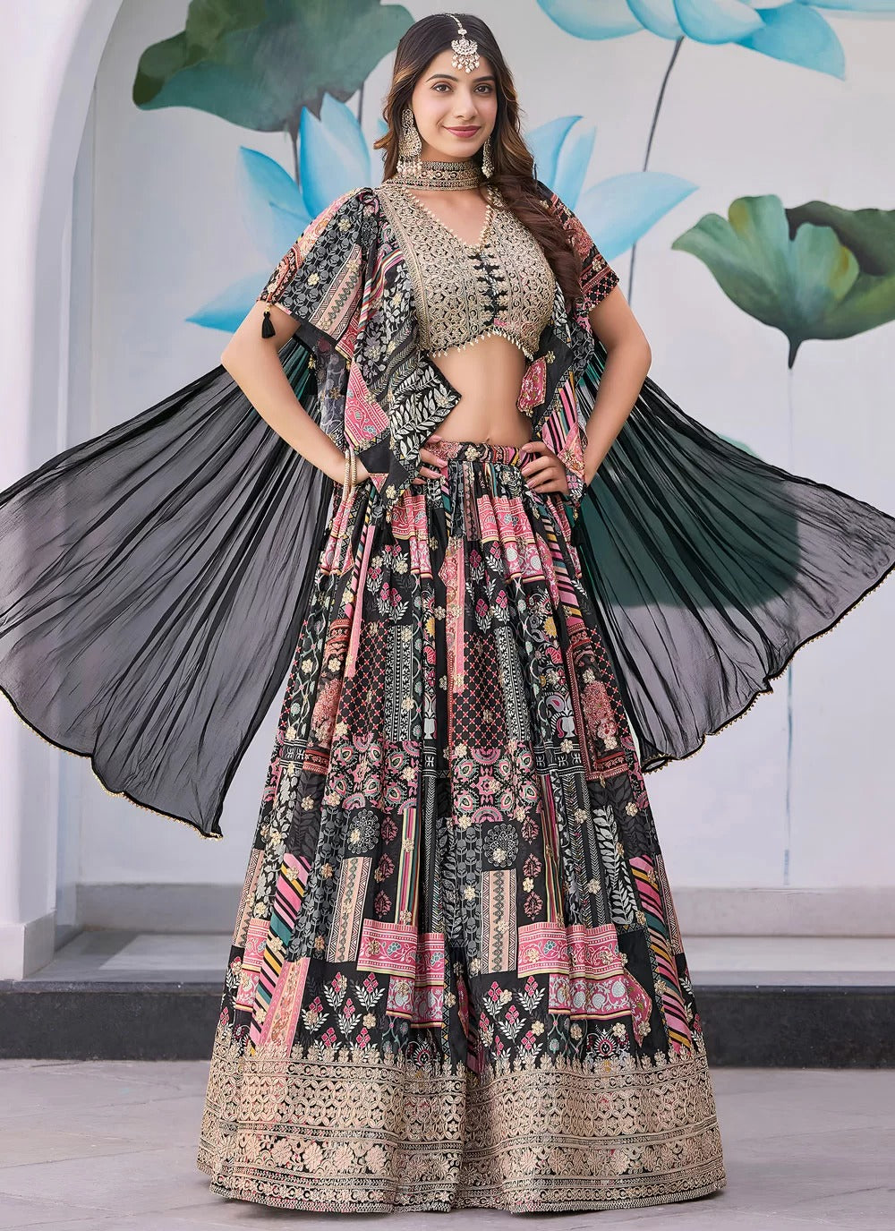 Woman wearing a traditional patterned outfit with a black dupatta against a decorative background