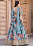 Woman in a traditional outfit with a blue dupatta standing in front of a textured wall.