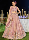 Woman in a pink embroidered traditional outfit at an outdoor event with candles and flowers.