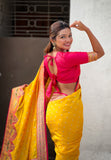 Woman in a yellow saree with pink blouse posing against a neutral background