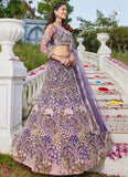Woman in a purple and gold embroidered traditional outfit standing on a decorative staircase with flowers.