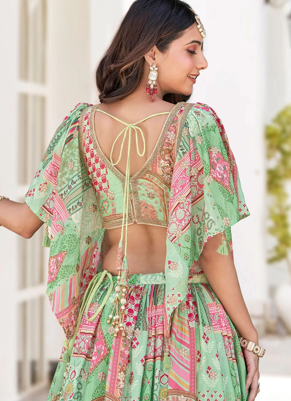 Woman wearing a green and pink traditional outfit with floral patterns.