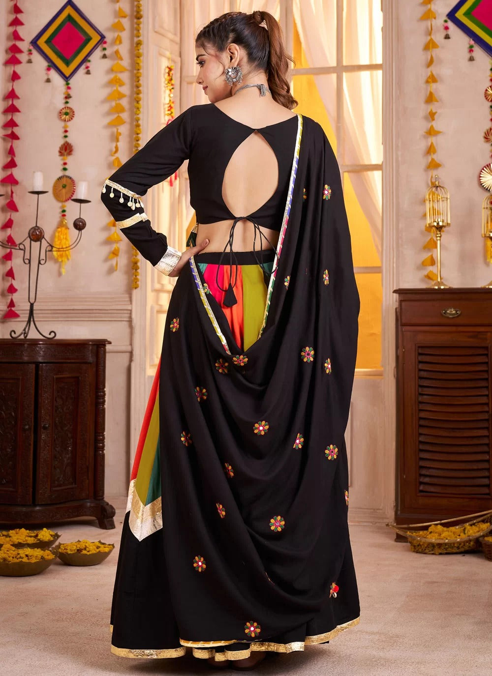 Woman in a black traditional outfit with colorful interior setting