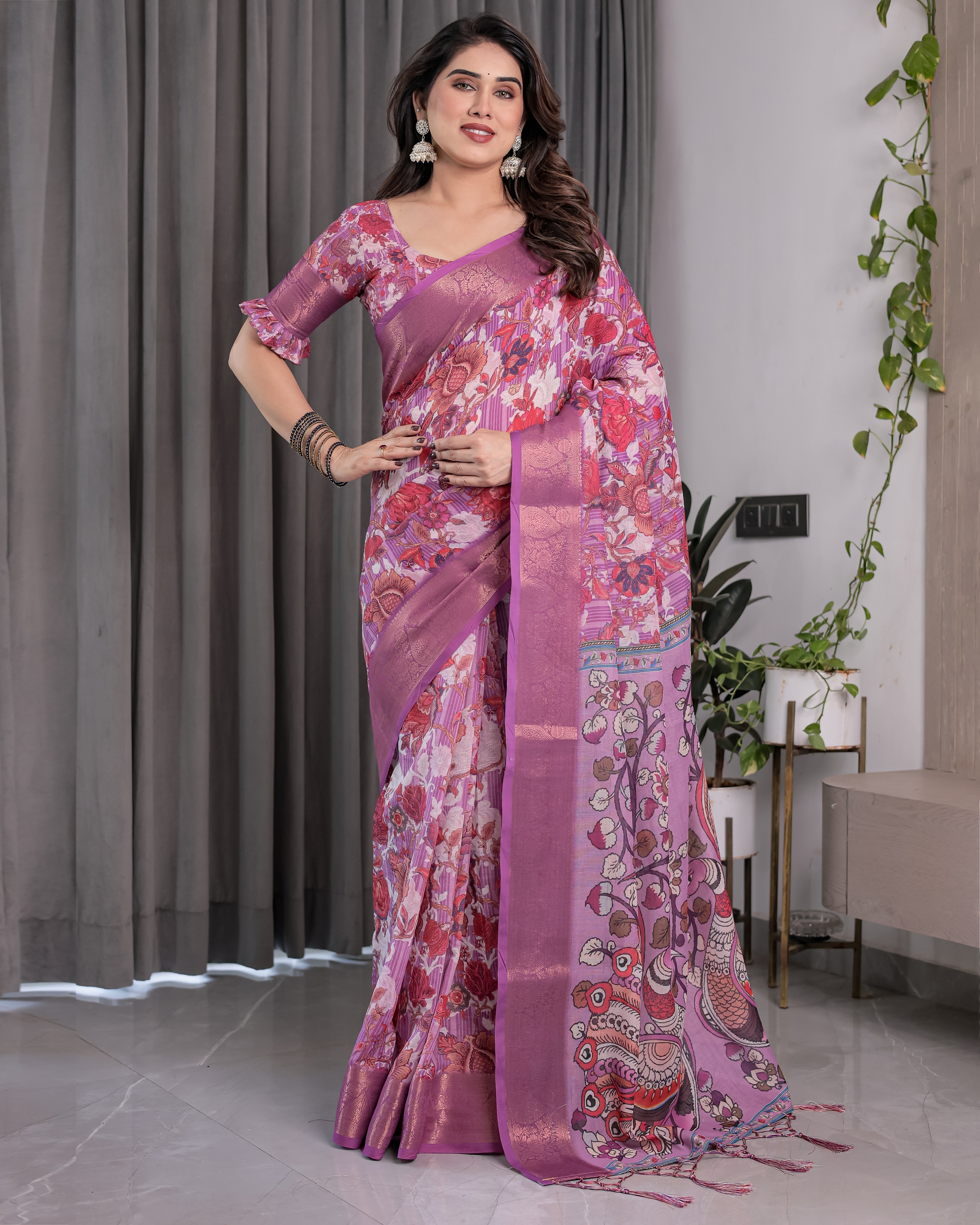 Woman wearing a pink saree with a floral pattern in an indoor setting.