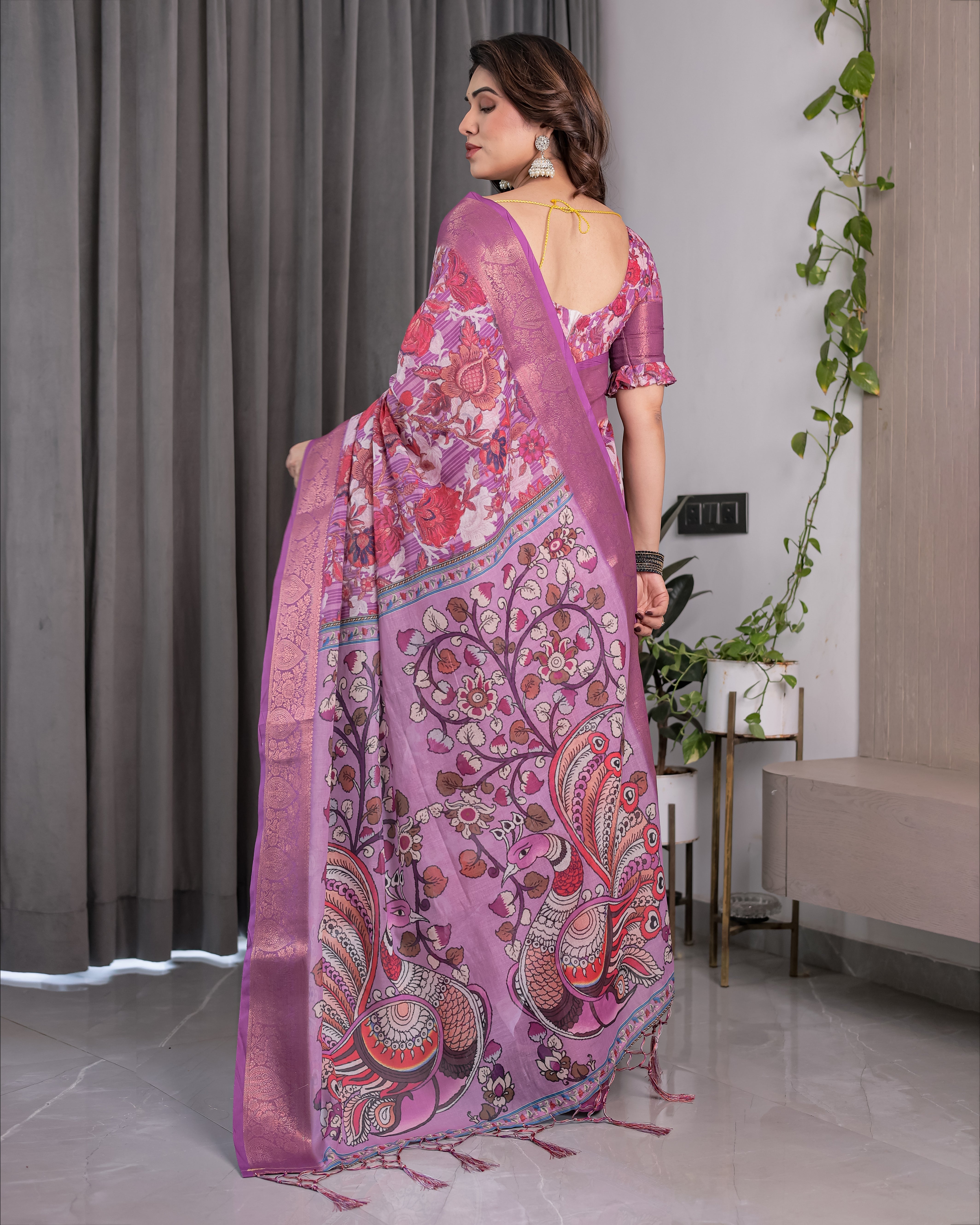 Woman wearing a pink saree with a floral pattern in a room.